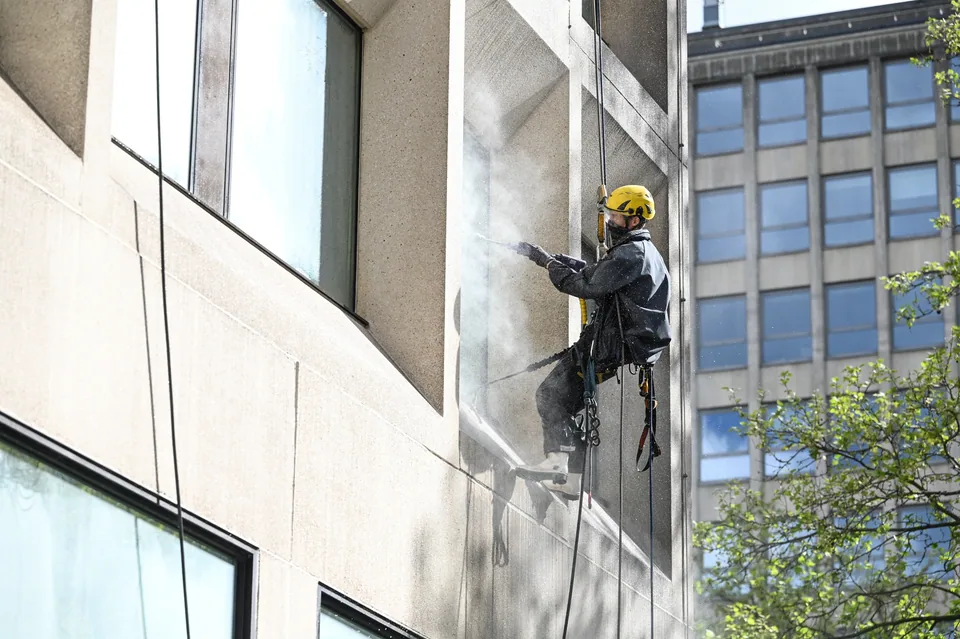 Nettoyage d’une façade en béton ou crépi par un cordiste.