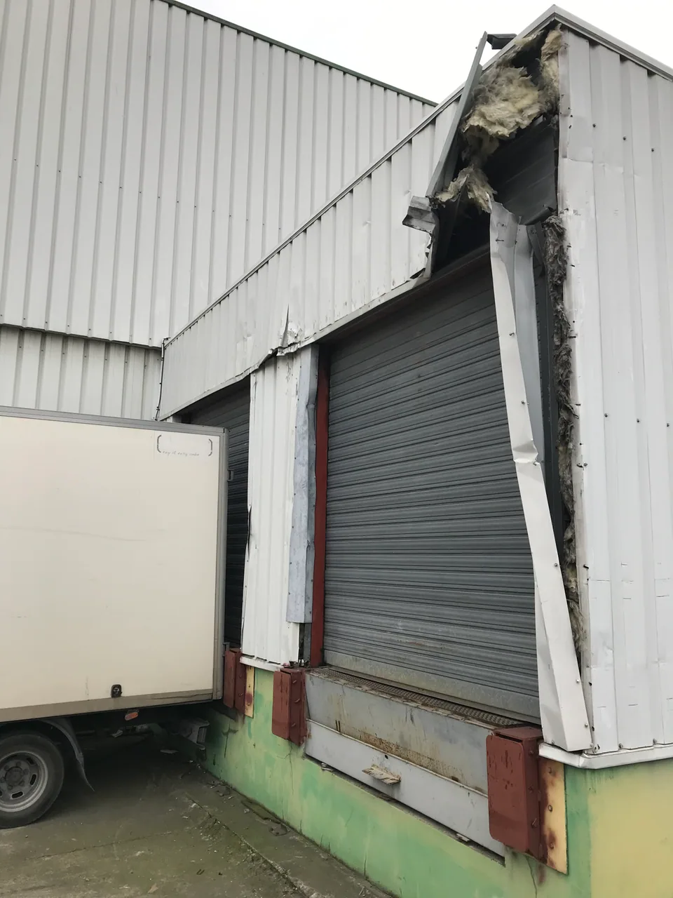 Bardage et habillage endommagés autour d’une porte de quai.